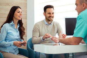 Dentist and couple talking in dental office