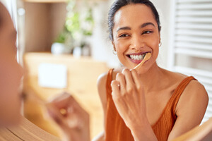 Woman smiling while brushing her teeth