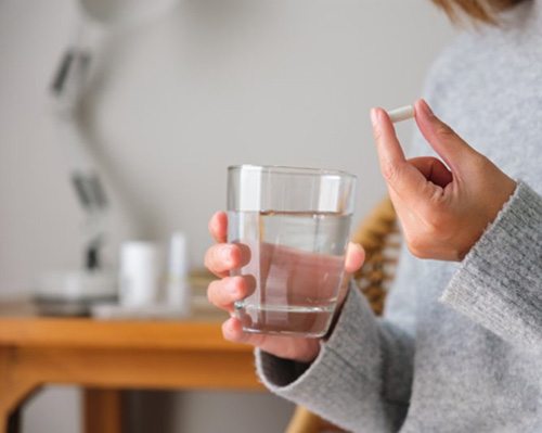 Lady holds pill and glass of water