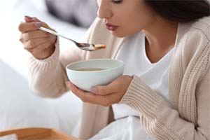 young woman eating soup after getting dental implants in Bedford