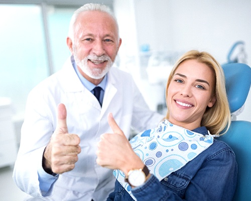 Dentist and female patient giving thumbs up sign 