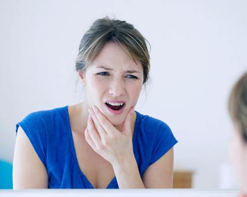 Woman touching her jaw, wearing pained expression