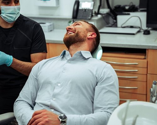 Male dental patient conversing with dentist