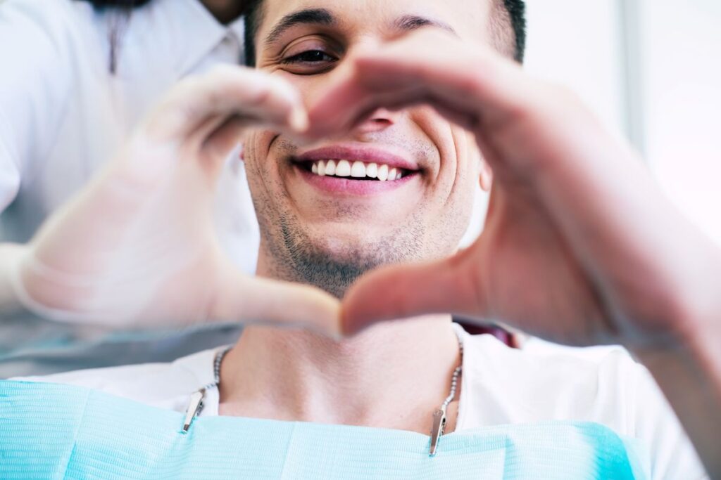 A man making a heart shape with his hands at the dentist